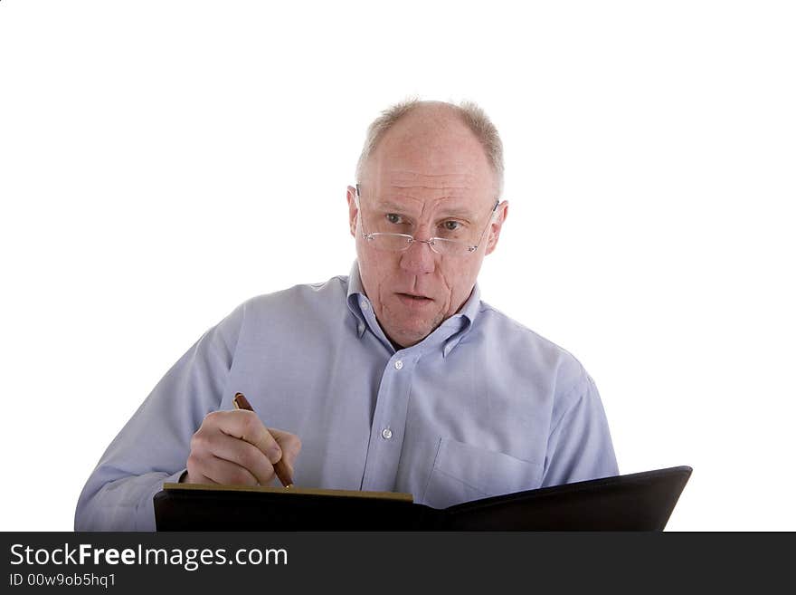 An older man in a blue dress shirt isolated on white taking notes in a black notebook or giving a lecture. An older man in a blue dress shirt isolated on white taking notes in a black notebook or giving a lecture