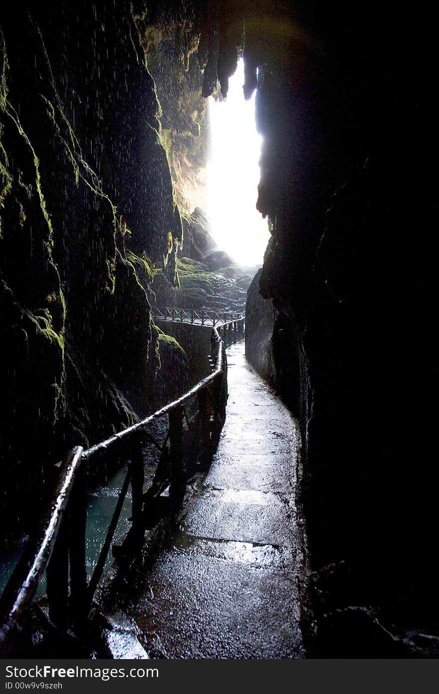 Stone path inside a grot with a wood balustrade and raining. Stone path inside a grot with a wood balustrade and raining