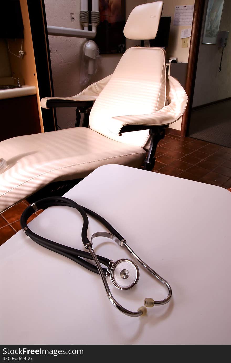 A stethoscope on a white table with medical dentists chair in background. A stethoscope on a white table with medical dentists chair in background.