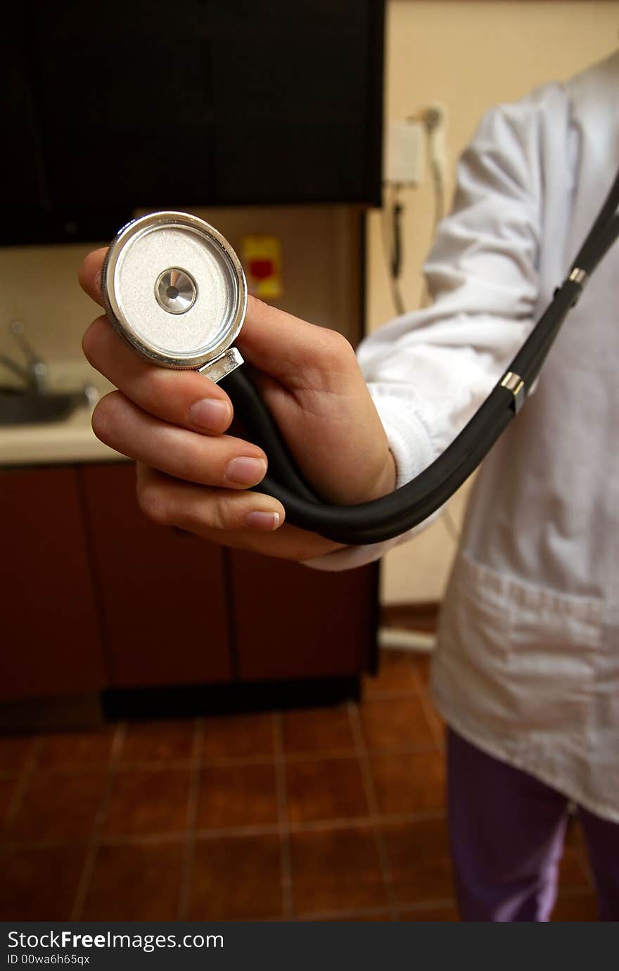 A stethoscope being held up to the camera lens being held by a female doctor in white lab coat. A stethoscope being held up to the camera lens being held by a female doctor in white lab coat.