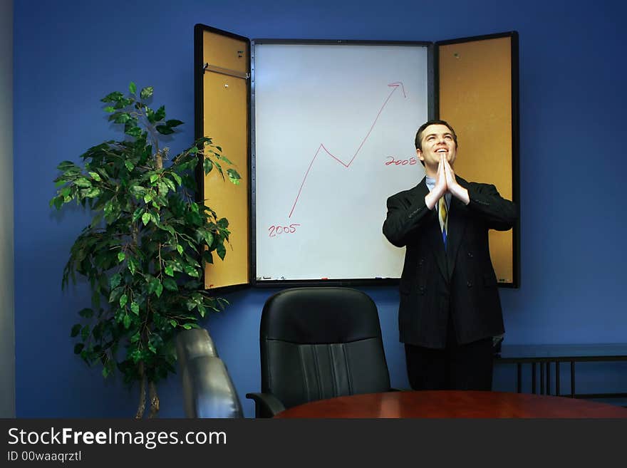 Businessman in a conference room with his hands joined praying for success. Businessman in a conference room with his hands joined praying for success