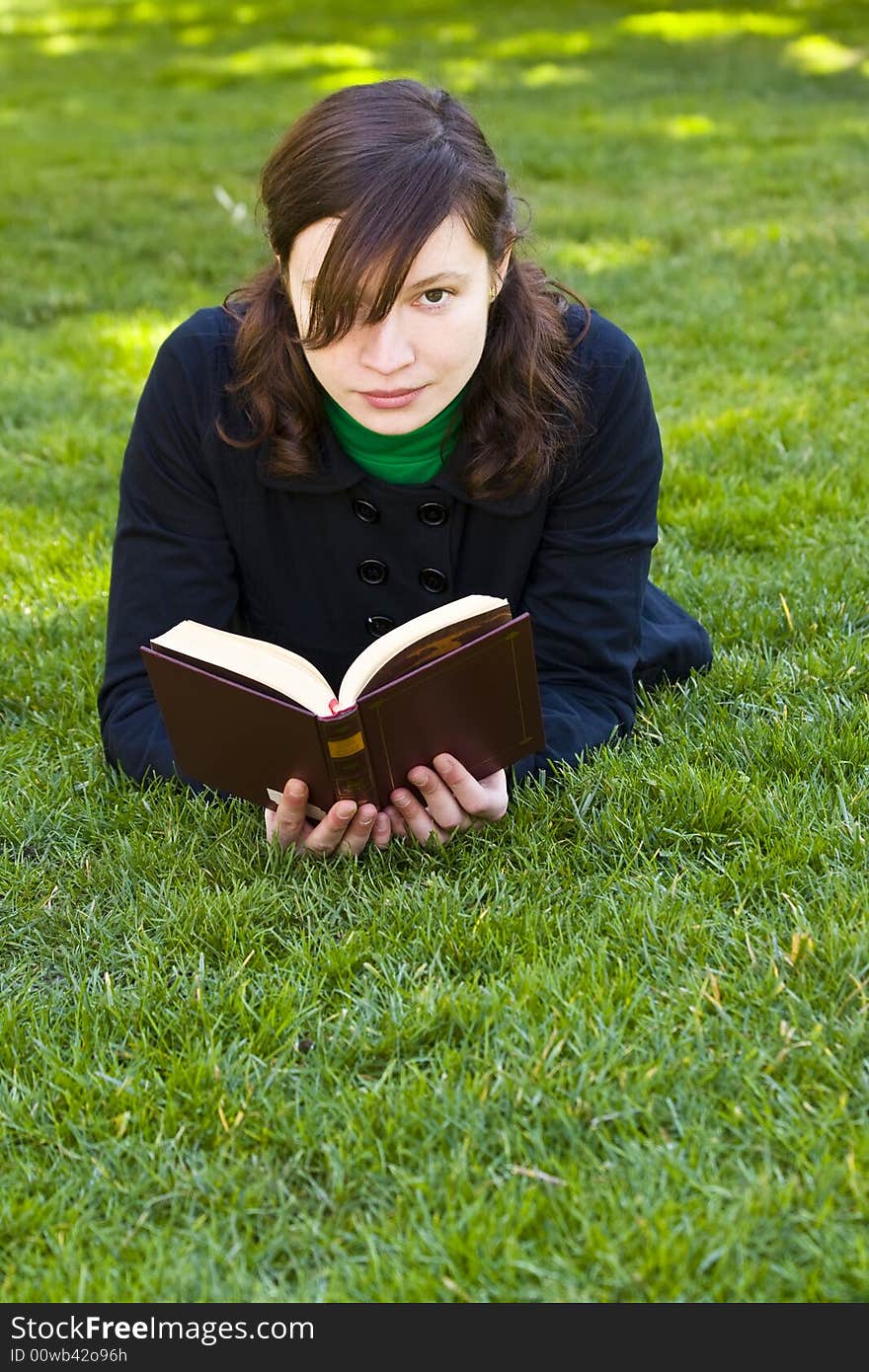 Beautiful brunette woman reading on the grass