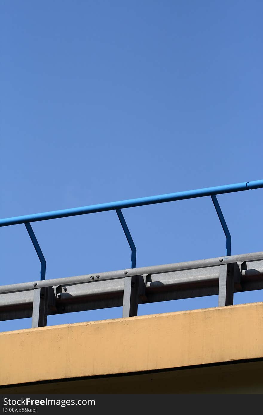 Close-up of bridge handrail over blue sky.