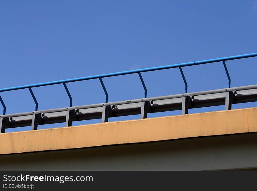 Close-up of bridge handrail over blue sky.