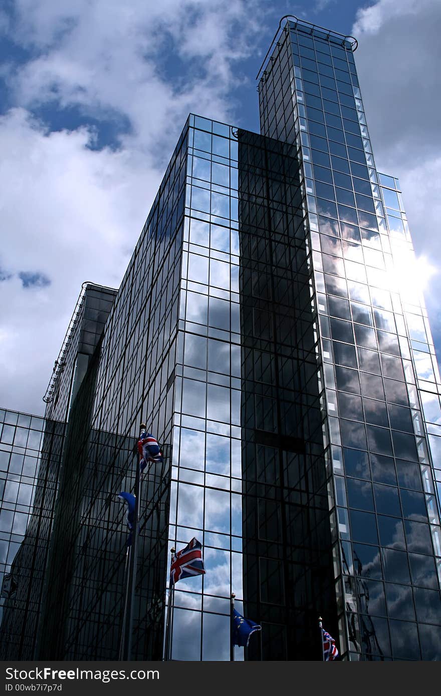 Modern blue glassed office building with flags outside