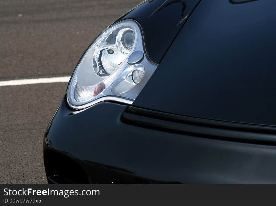 Black supercar headlight with concrete background