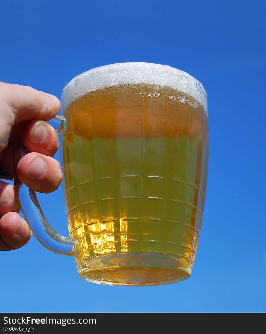 Hand with beer mug over a blue background