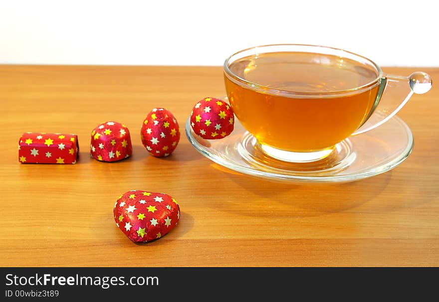 Chocolates in a red wrapper and a cup of tea. Chocolates in a red wrapper and a cup of tea