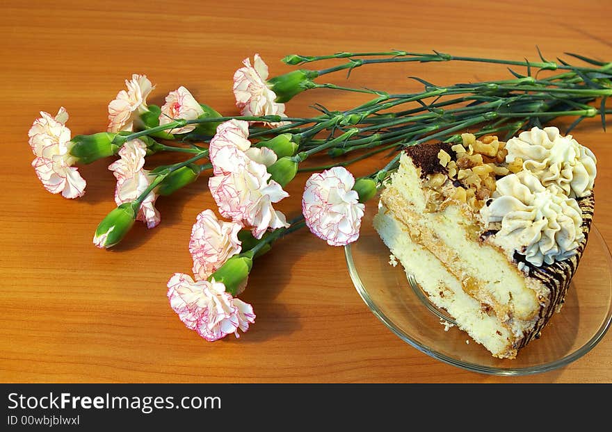 Bouquet of pink carnations and piece of a cake. Bouquet of pink carnations and piece of a cake