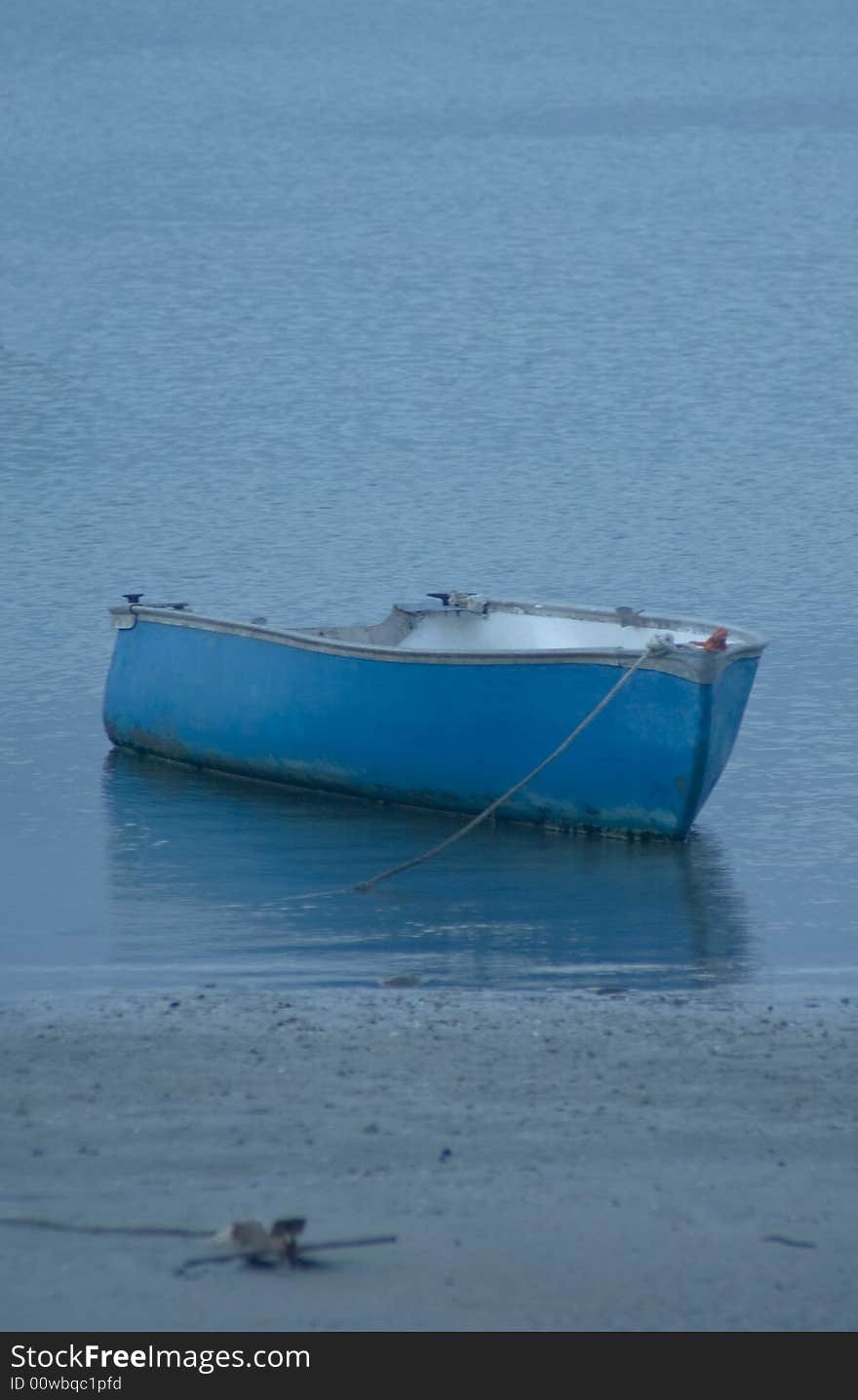 Blue boat anchored off the sand in bay