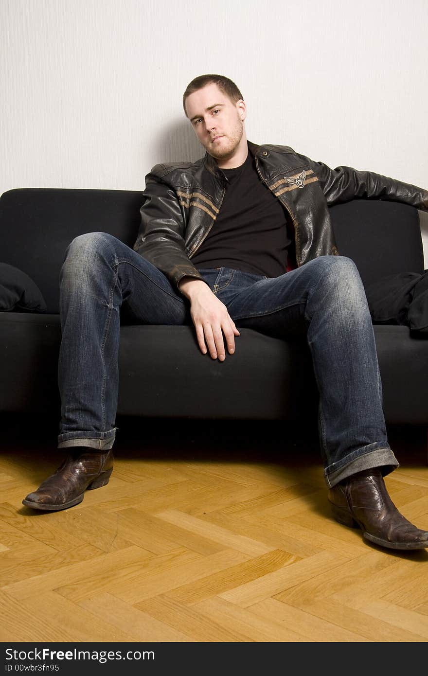 Young man sitting on a black sofa. Young man sitting on a black sofa