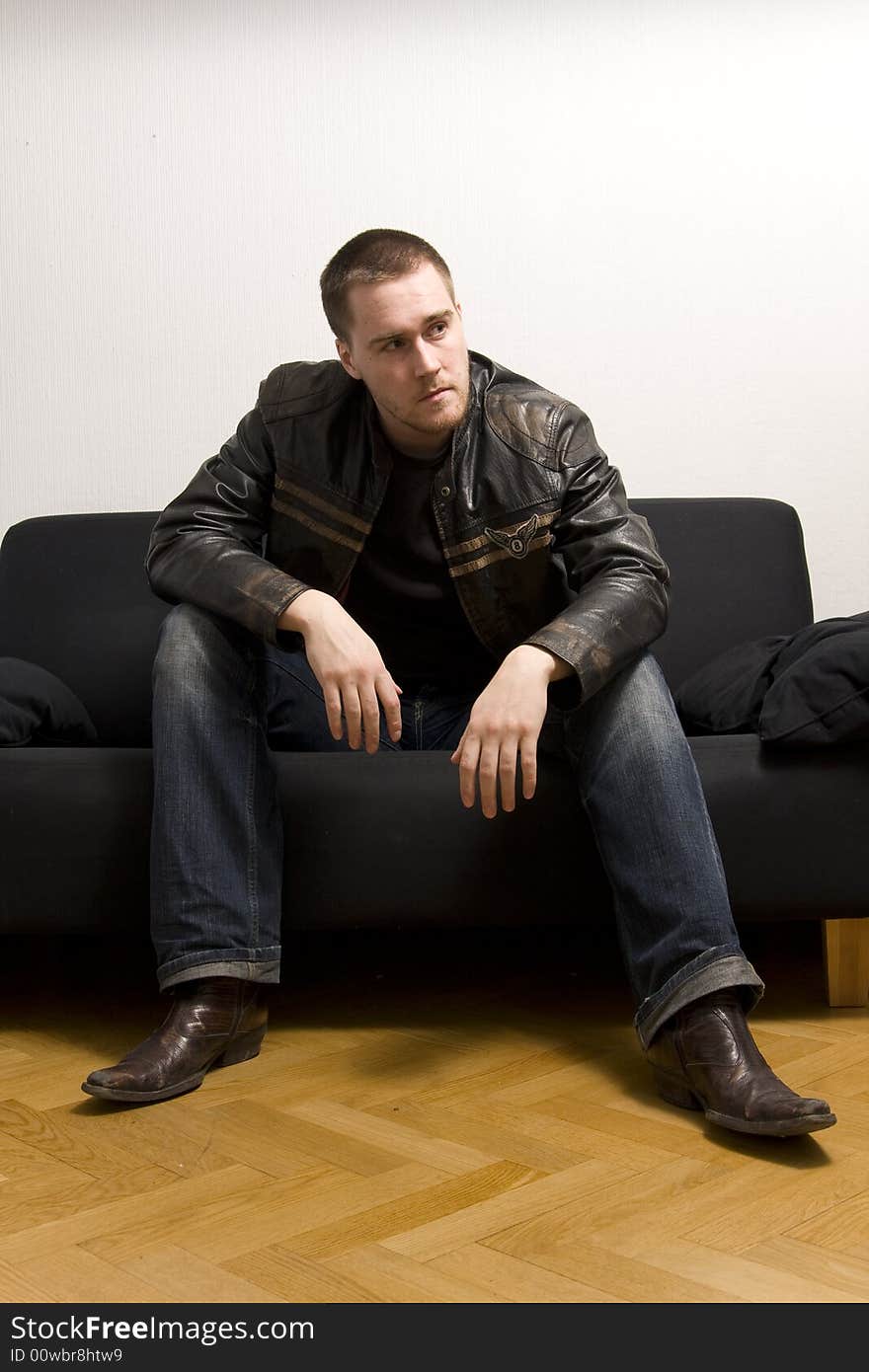 Young man sitting on a black sofa. Young man sitting on a black sofa