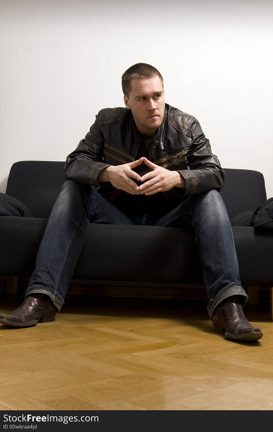 Young man sitting on a black sofa. Young man sitting on a black sofa