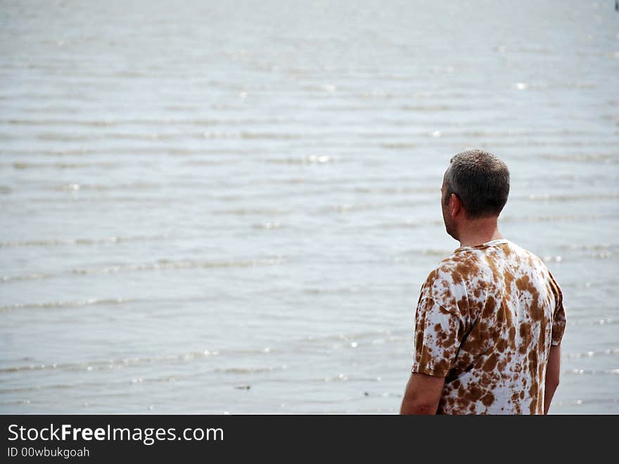 Man looking out to a hazy sea on a warm spring day