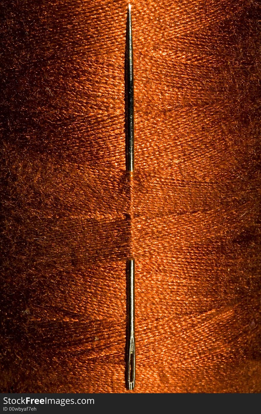 Needle stitched through thread on a roll of thread. Needle stitched through thread on a roll of thread.