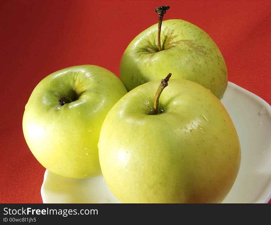 Three green apples on red