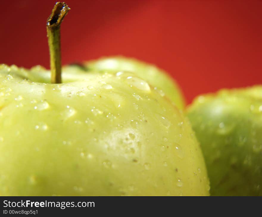 Fresh green apples closeup with water drops and red background. Fresh green apples closeup with water drops and red background