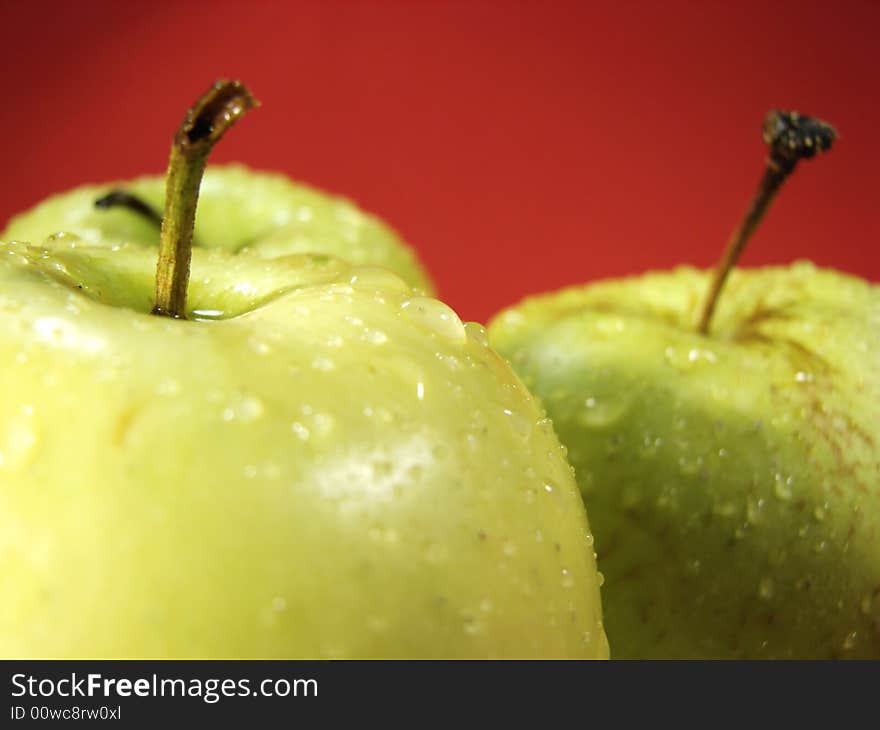 Fresh green apples closeup with water drops and red background. Fresh green apples closeup with water drops and red background