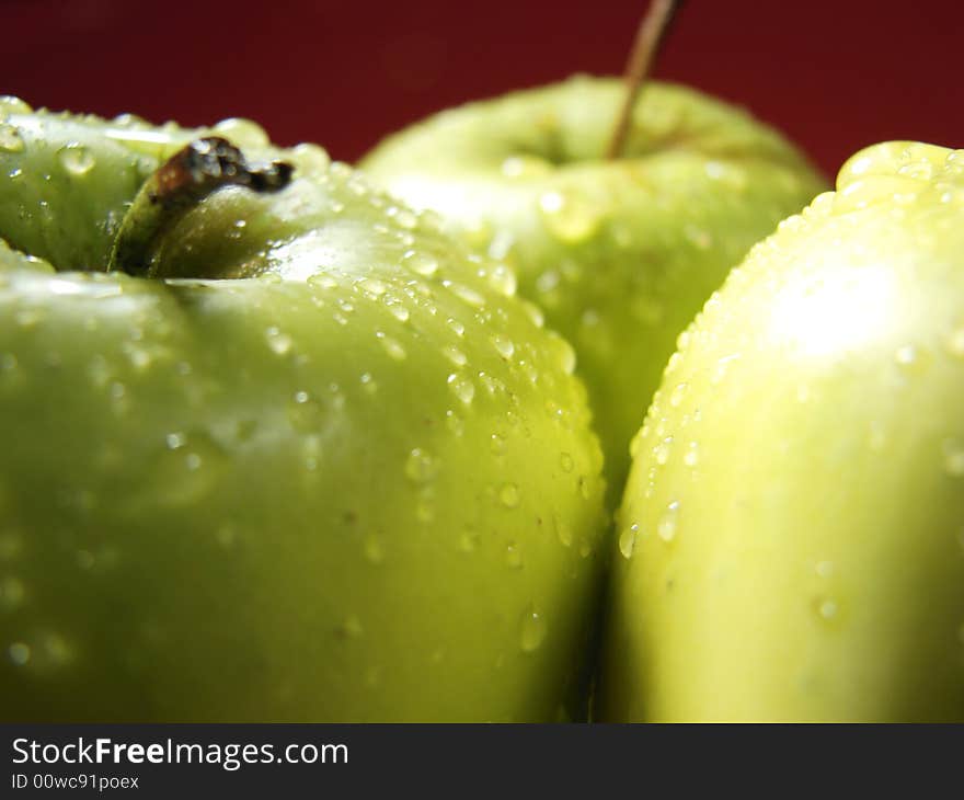 Fresh green apples closeup with water drops and red background. Fresh green apples closeup with water drops and red background