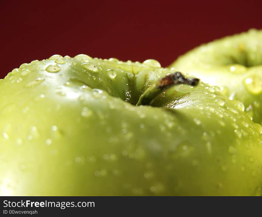 Fresh green apples closeup with water drops and red background. Fresh green apples closeup with water drops and red background