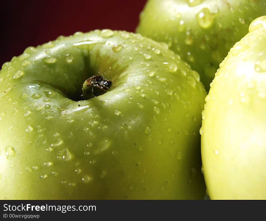 Fresh green apples closeup with water drops and red background. Fresh green apples closeup with water drops and red background