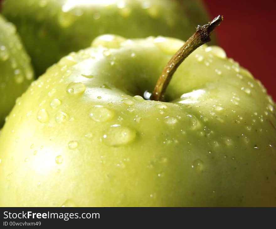 Fresh green apples closeup with water drops and red background. Fresh green apples closeup with water drops and red background