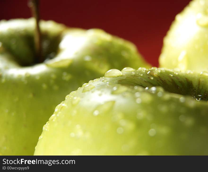 Fresh green apples closeup with water drops and red background. Fresh green apples closeup with water drops and red background