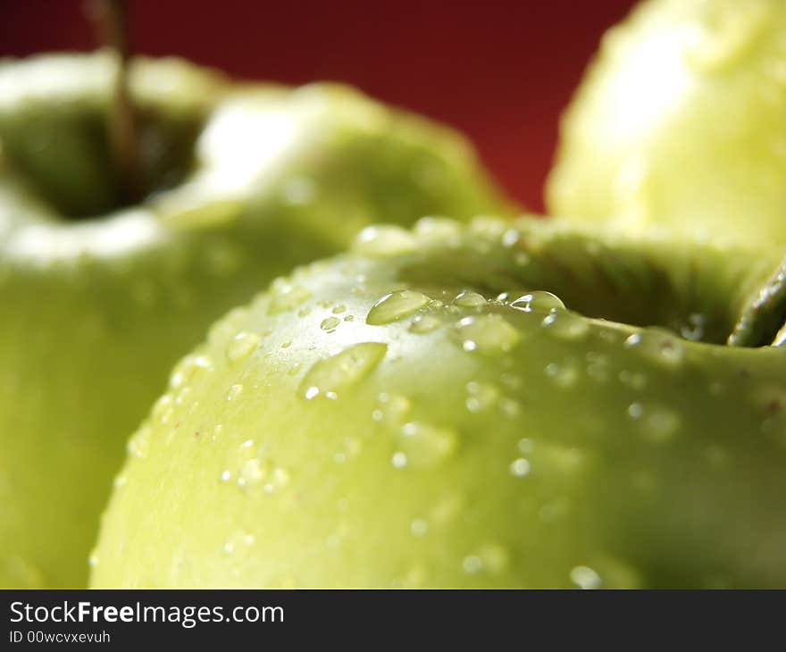 Fresh green apples closeup with water drops and red background. Fresh green apples closeup with water drops and red background