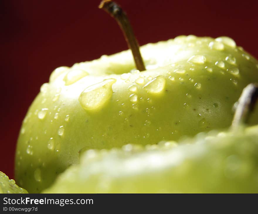 Fresh green apples closeup with water drops and red background. Fresh green apples closeup with water drops and red background