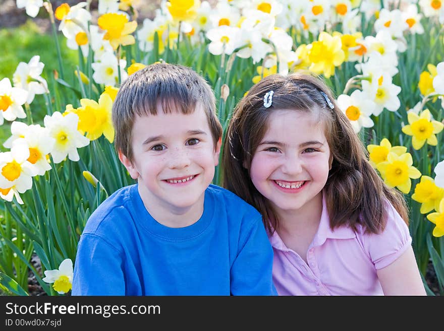 Two Little Friends Sitting in Front of Daffodils. Two Little Friends Sitting in Front of Daffodils