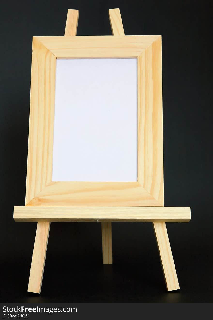 A blank wood framed picture sits on an easel in the vertical. A blank wood framed picture sits on an easel in the vertical