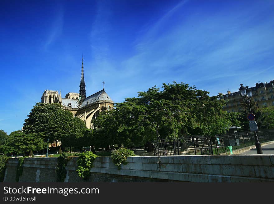 Notre Dame basilica in Paris, also known as Notre-Dame de Paris on spring blue sky and grenn trees.