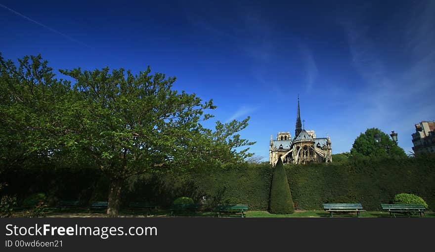 Panoramic view Notre Dame basilica in Paris, also known as Notre-Dame de Paris on spring blue sky and grenn trees.