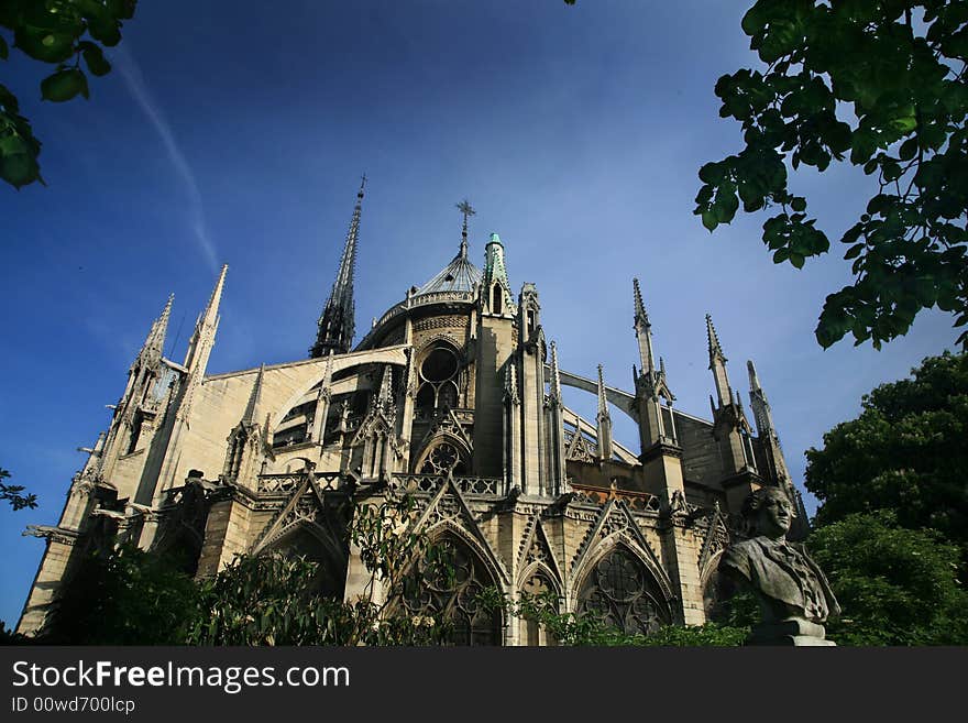 Notre Dame basilica in Paris, also known as Notre-Dame de Paris on spring blue sky and grenn trees.