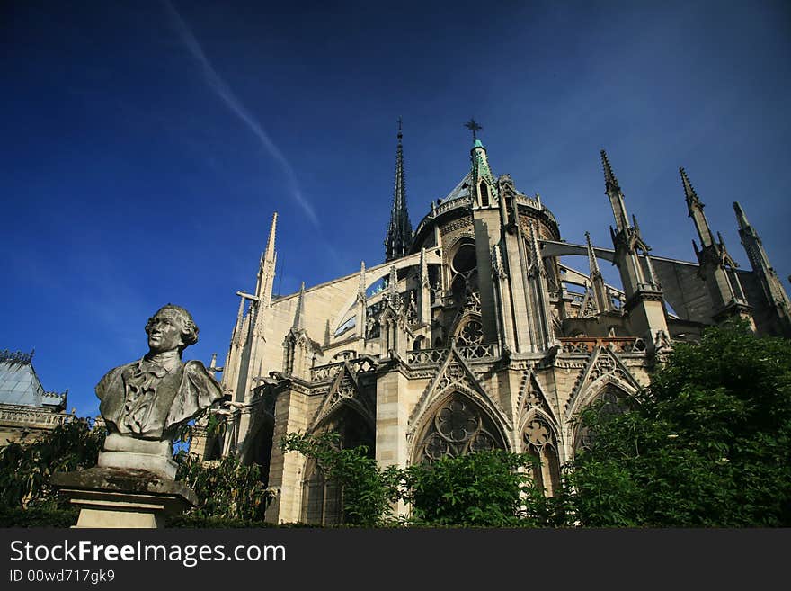 Notre Dame basilica in Paris, also known as Notre-Dame de Paris on spring blue sky and grenn trees.