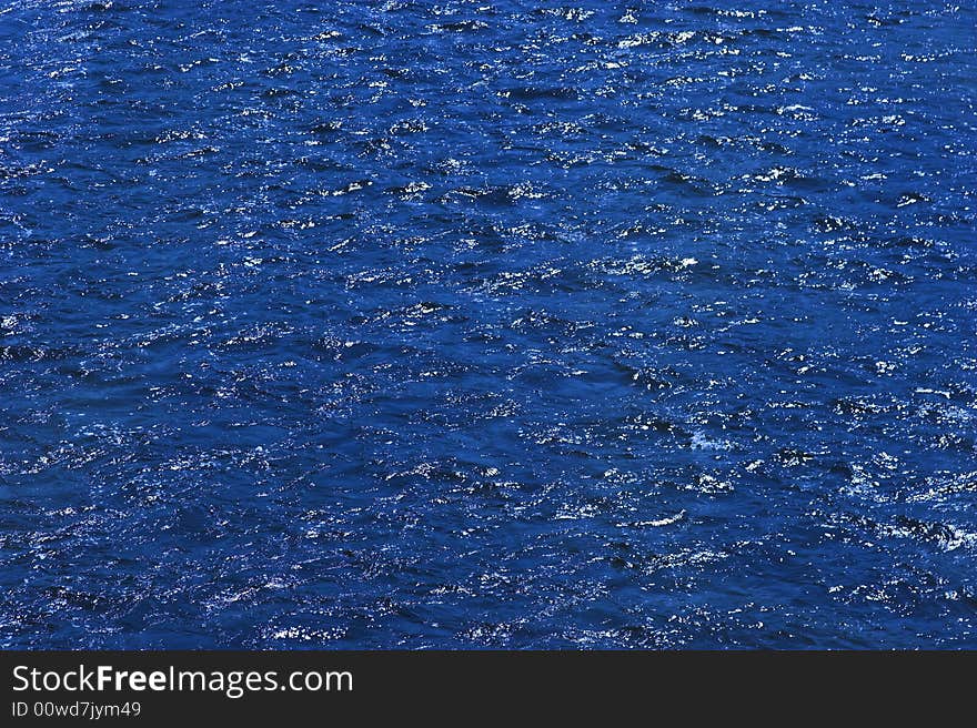 Dark blue water with small wave with highlights from a sunny day. Dark blue water with small wave with highlights from a sunny day.