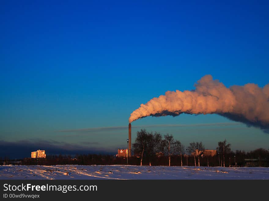 Factory smoke on blue sky in winter sunset