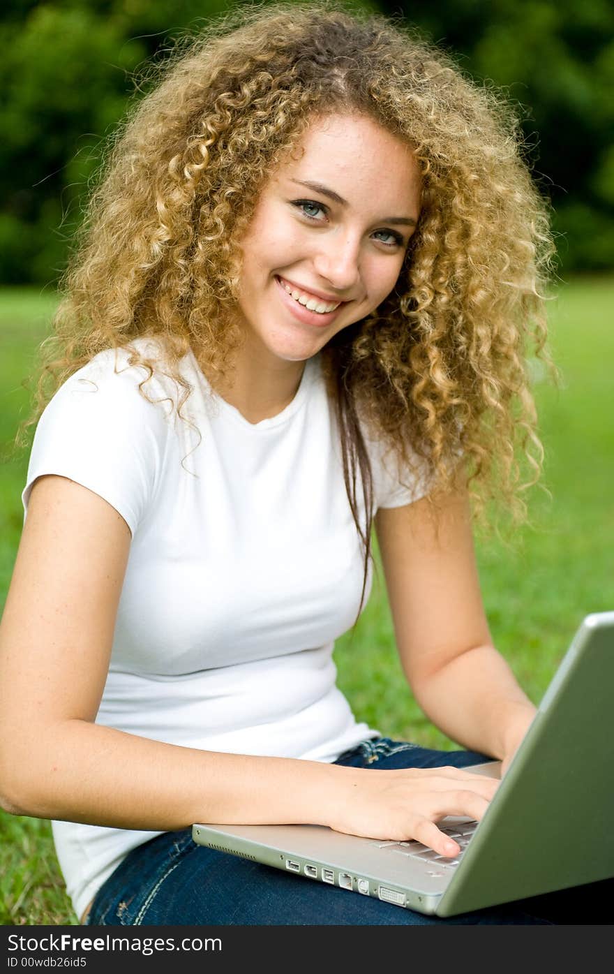 A beautiful young woman using a portable computer outside. A beautiful young woman using a portable computer outside