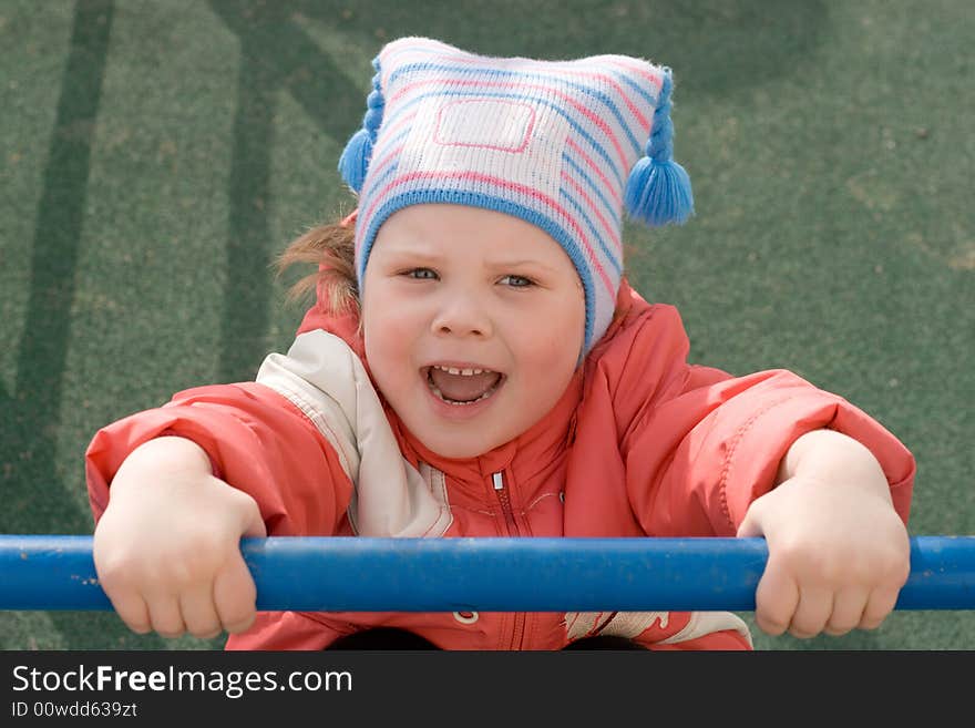 A little girl hanging on the horizontal bar at the playground. A little girl hanging on the horizontal bar at the playground