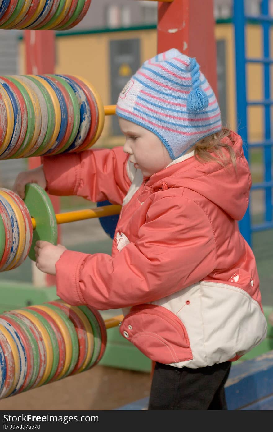 A pretty young girl playing with big wooden abacus. A pretty young girl playing with big wooden abacus