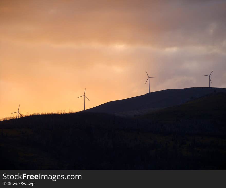 Wind turbines generating energy on a hill at sunset