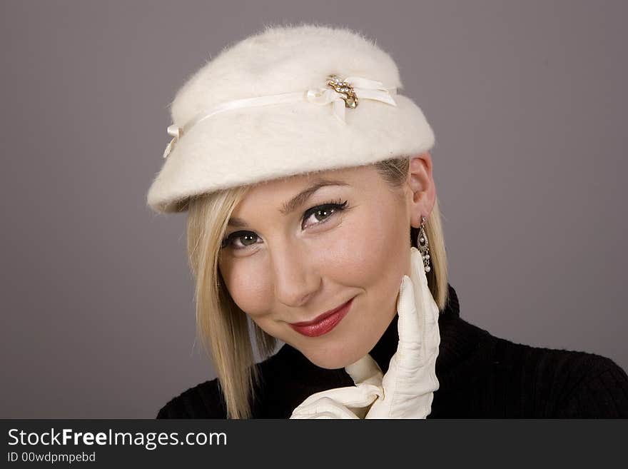 A blonde in a black turtleneck and a white fur hat wearing white gloves. A blonde in a black turtleneck and a white fur hat wearing white gloves