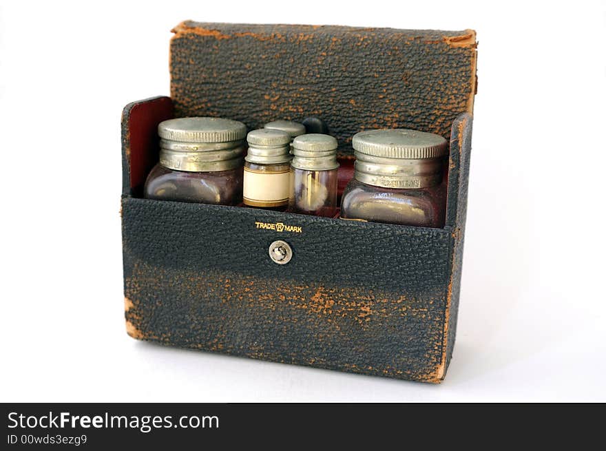 A vintage, distressed leather pharmaceutical case with a red lining, filled with two large bottles and three small vials. One of the vials has a blank label facing forwards. A vintage, distressed leather pharmaceutical case with a red lining, filled with two large bottles and three small vials. One of the vials has a blank label facing forwards.