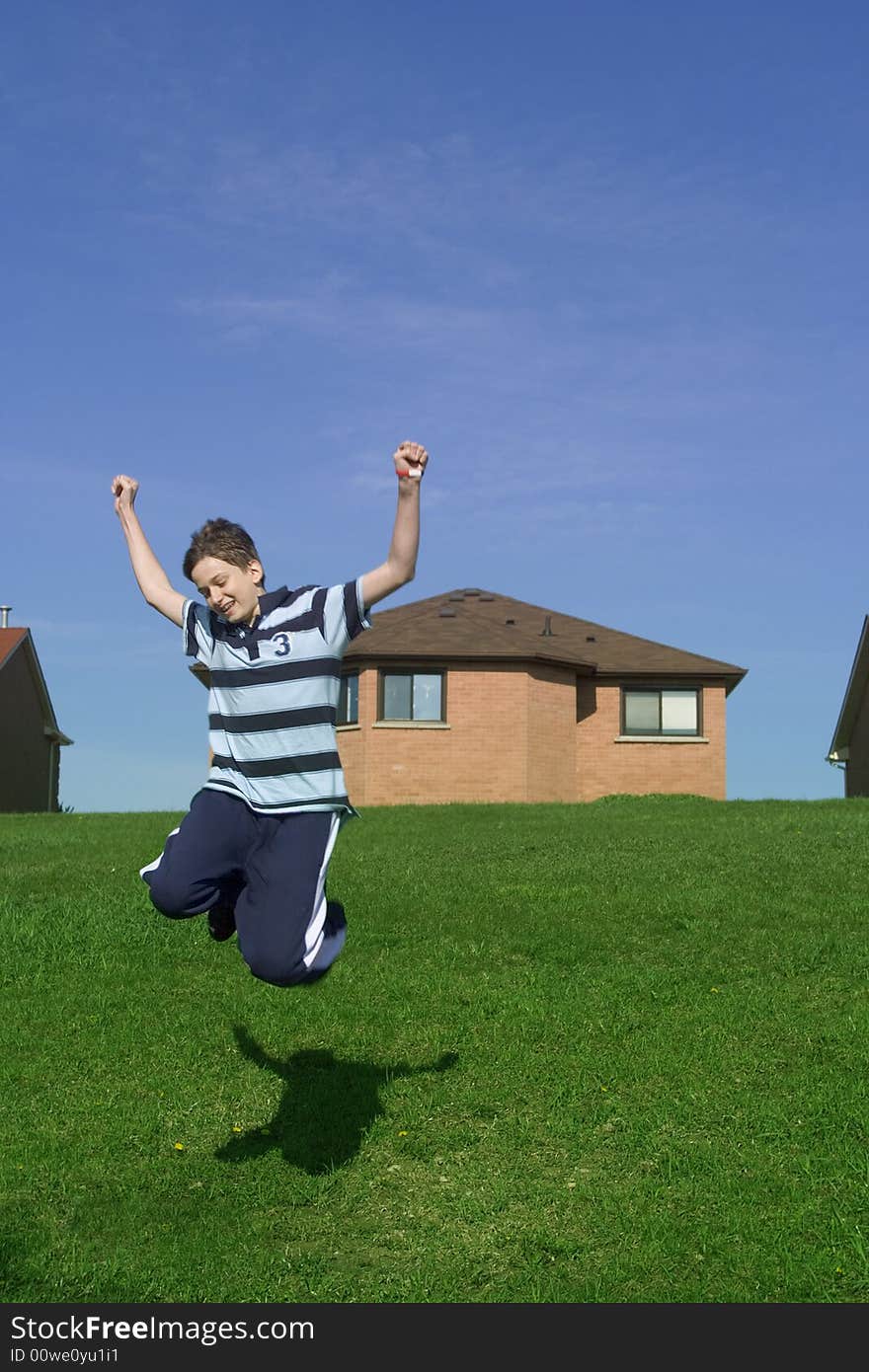 Happy teenager jumping, suburbs in the background