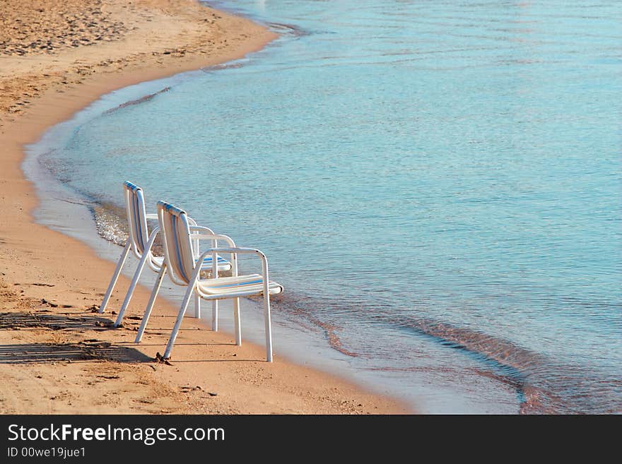 Two empty beach chairs on a lonely quite beach early in the morning. The location is at Hurghada, Egypt. Two empty beach chairs on a lonely quite beach early in the morning. The location is at Hurghada, Egypt.