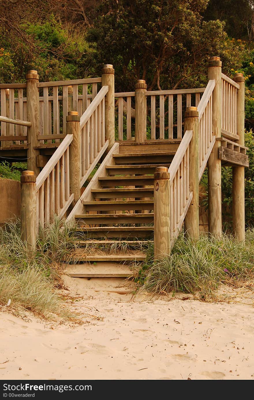 A set of timber steps leading down onto a sandy beach. A set of timber steps leading down onto a sandy beach