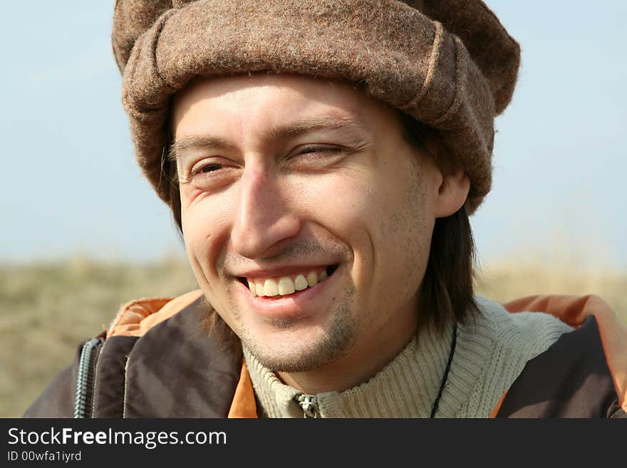 Portrait of happy man in hat on background of nature