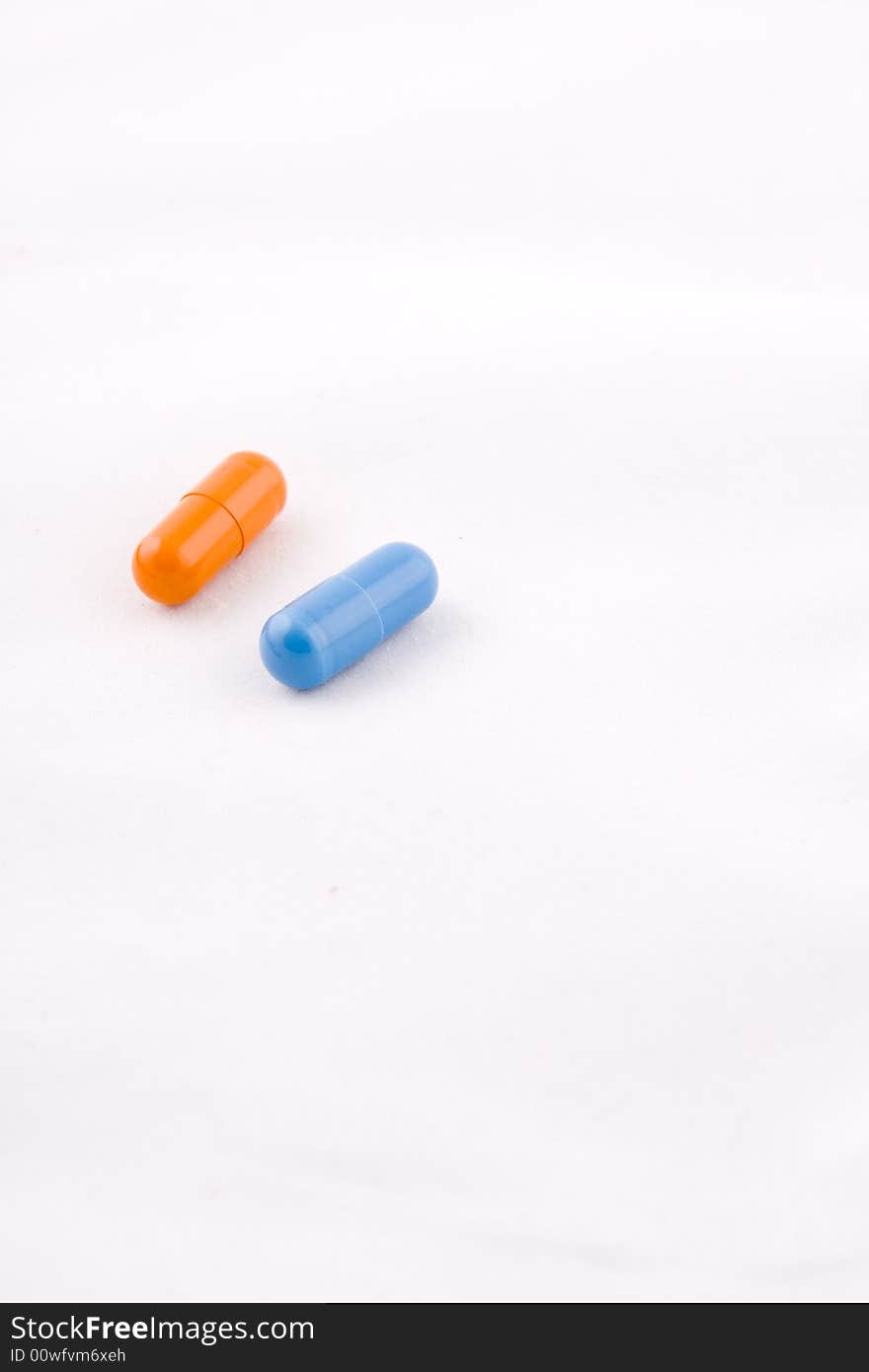 Pair of blue and orange pills, white background