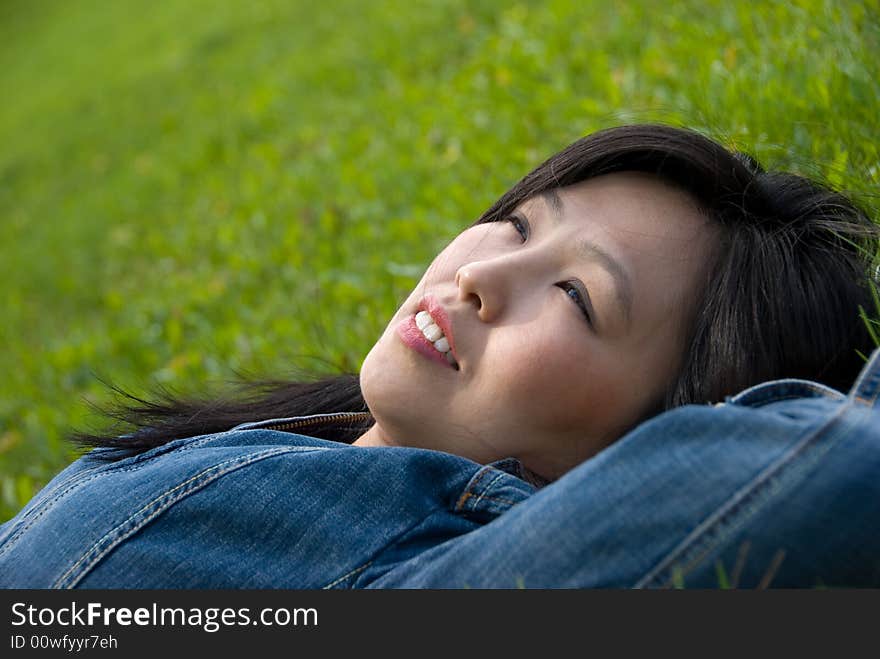 Dreams in the grass - young attractive woman  relaxes in the park