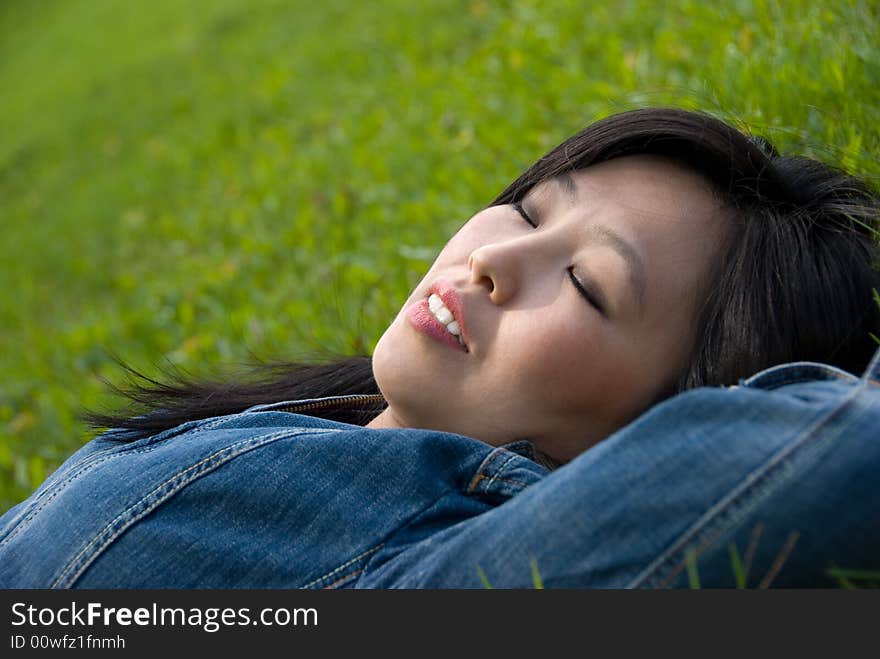 Dreams in the grass - young attractive woman relaxes in the park